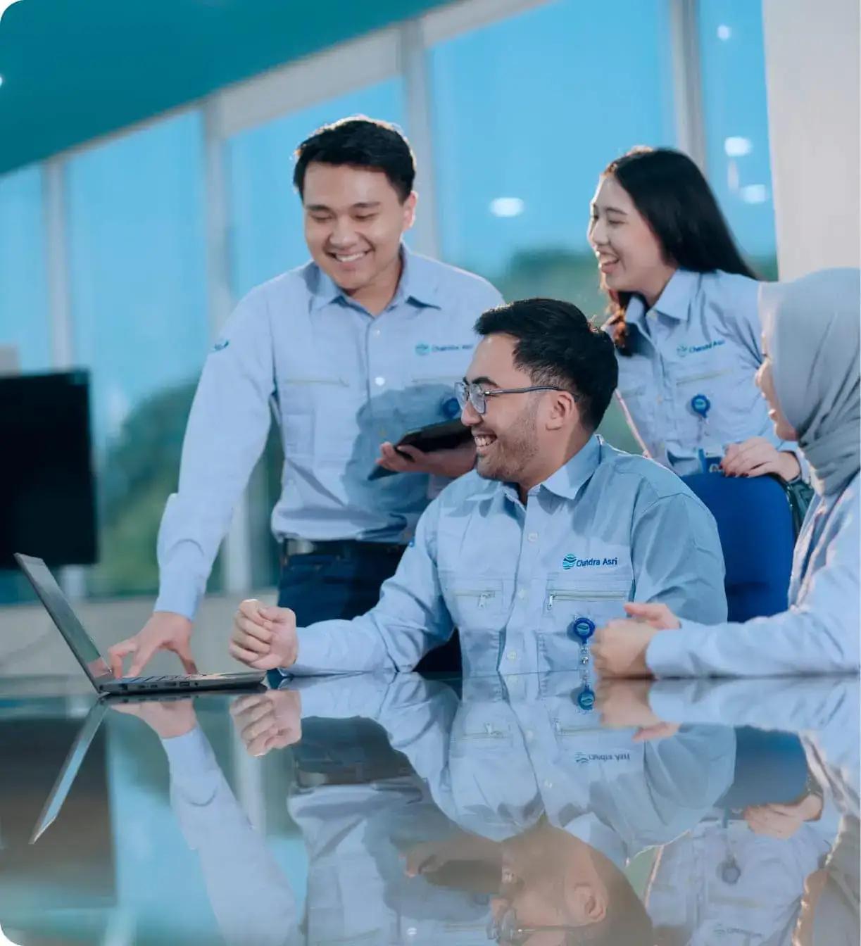 Tim profesional berdiskusi dengan semangat, mengenakan seragam Chandra Asri di ruang kerja